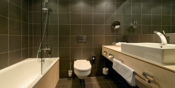 Modern bathroom with bathtub, shower, WC and washbasin in the ATLANTIC Hotel Sail City, Bremerhaven.