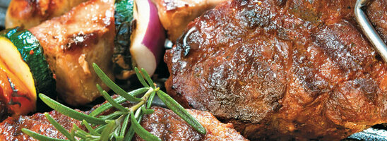 Barbecue with steak, sausage, vegetable skewers, corn on the cob and tomatoes, all freshly prepared at the ATLANTIC Hotel Wilhelmshaven.