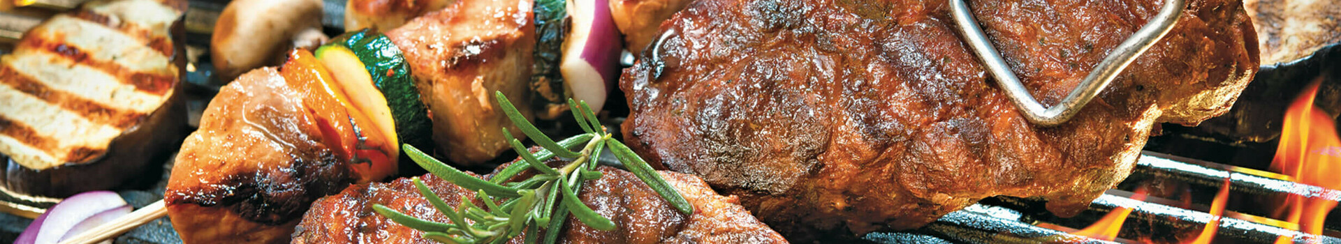 Grill mit Steak, Wurst, Gemüsespießen, Maiskolben und Tomaten, alles frisch zubereitet im ATLANTIC Hotel Wilhelmshaven.