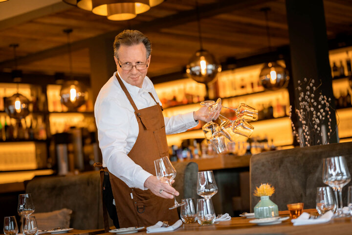 Moderne Restaurants im ATLANTIC Hotel Landgut Horn Bremen Ein Kellner deckt elegant einen Tisch im stilvollen Restaurant des ATLANTIC Hotel Landgut Horn.