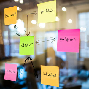 Conference concept SMART by ATLANTIC Hotels Colorful sticky notes with words like "SMART", "competent" and "modern" are stuck on a glass wall in an office.