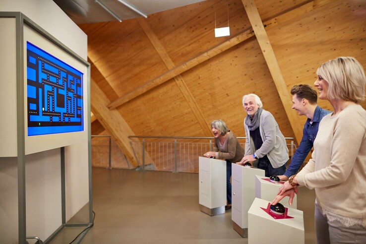 Personen spielen lachend ein Retro-Videospiel im Universum, Bremen.