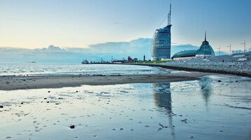 ATLANTIC Hotel Sail City exterior view ATLANTIC Hotel Sail City in Bremerhaven, modern building on the shore, reflected in the calm water at sunset.