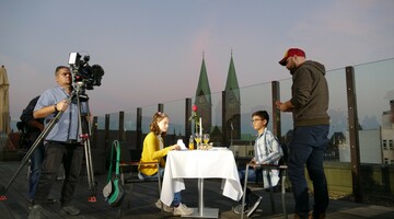 Zwei Kinder essen auf einer Hotel-Dachterrasse, gefilmt bei Sonnenuntergang mit Blick auf Kirchtürme.
