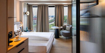 An armchair, a coffee machine and a bed in a single room.