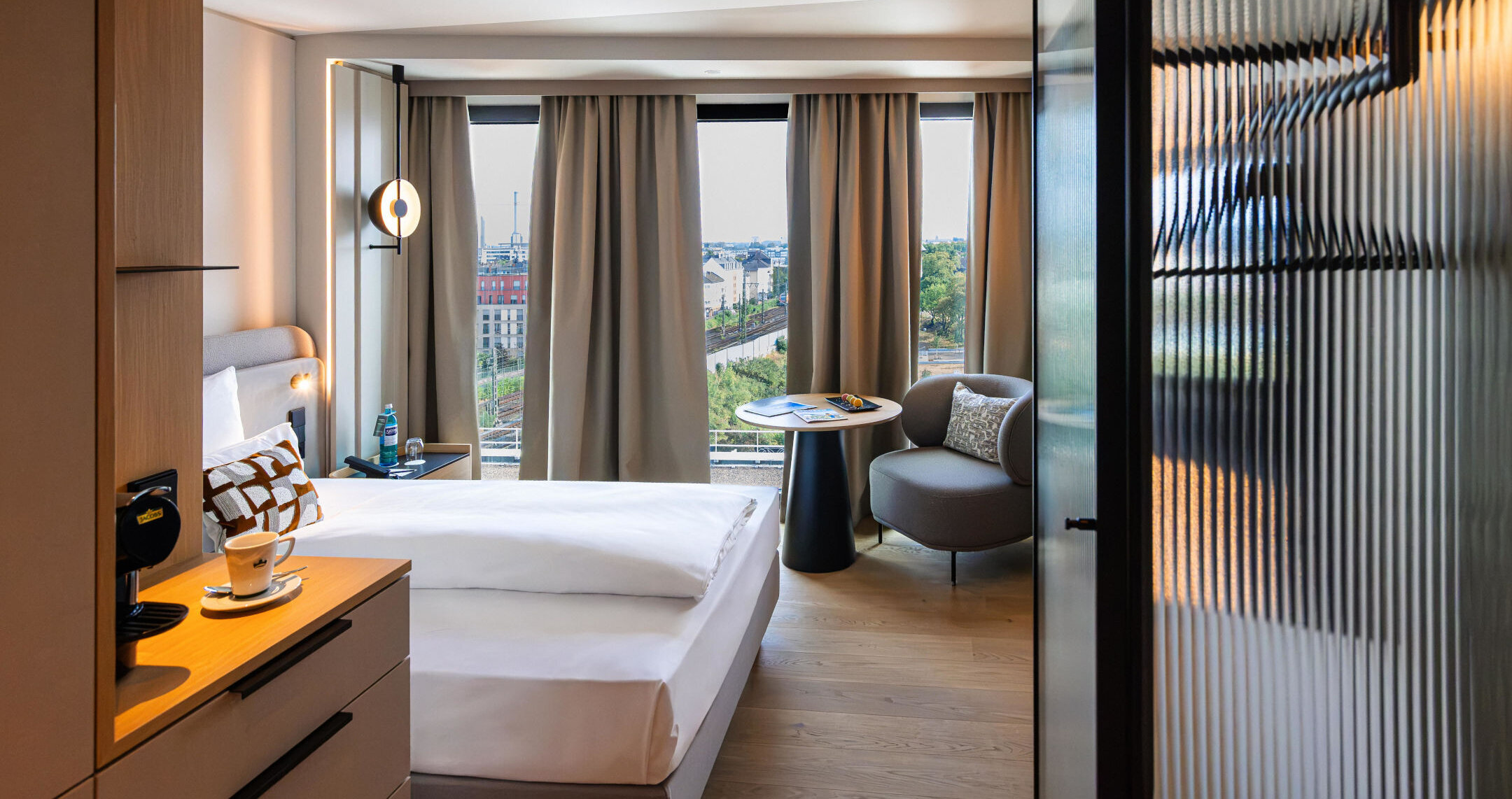 An armchair, a coffee machine and a bed in a single room.