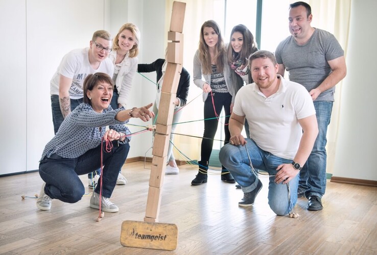 Group of people playing a team game with wooden blocks at the ATLANTIC Grand Hotel Travemünde.