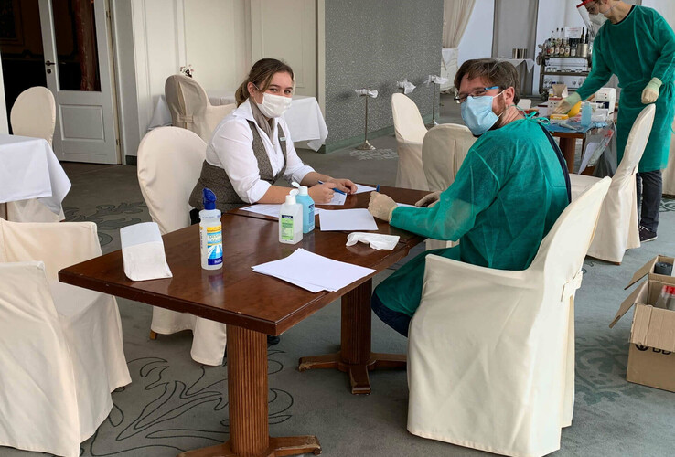 Tourismus Studie - Corona-Testung | ATLANTIC Grand Hotel Travemünde Hotelmitarbeiter in Schutzkleidung an einem Tisch mit Desinfektionsmitteln im ATLANTIC Grand Hotel Travemünde.