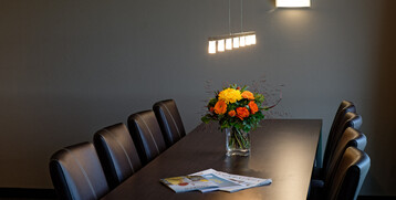 Modern conference table with leather armchairs, bouquet of flowers and magazines at the ATLANTIC Hotel Galopprennbahn Bremen.