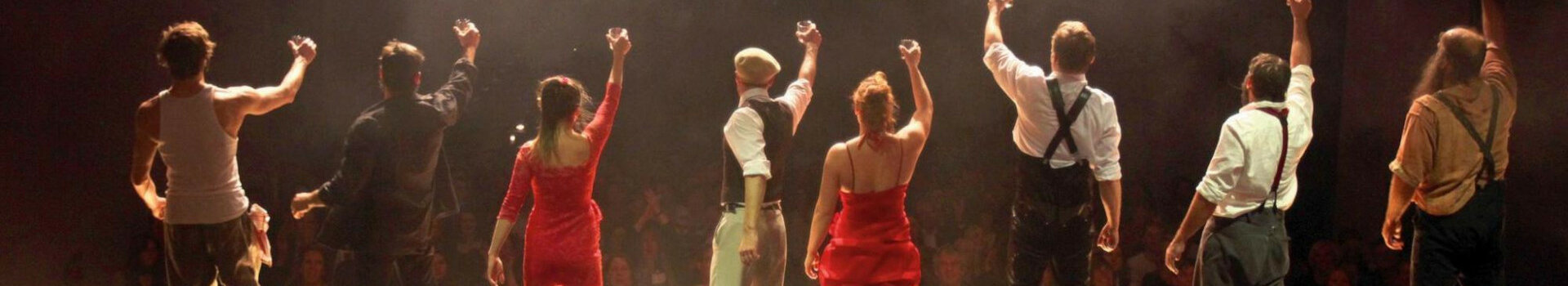 Angebot Magic Moments im ATLANTIC Hotel Münster mit Eintritt ins GOP Varieté-Theater Eine Gruppe von acht Künstlern hebt auf einer Bühne feierlich Gläser vor einem applaudierenden Publikum.