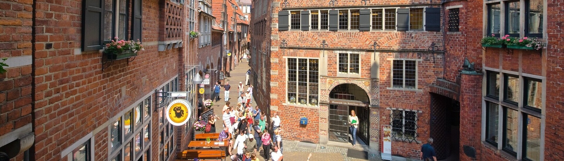Böttcherstraße in Bremen Historische Backsteingasse mit Fachwerkhäusern, Menschen spazieren und sitzen im Straßencafé bei sonnigem Wetter.
