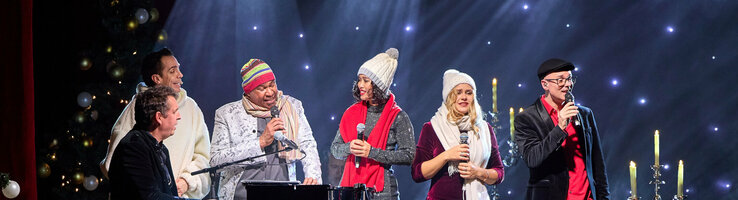 ATLANTIC Hotel Münster Firmenweihnachtsfeier im Engelsaal Eine Gruppe von Menschen singt auf einer Bühne mit festlicher Beleuchtung und Dekoration.
