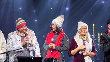 ATLANTIC Hotel Münster Firmenweihnachtsfeier im Engelsaal Eine Gruppe von Menschen singt auf einer Bühne mit festlicher Beleuchtung und Dekoration.