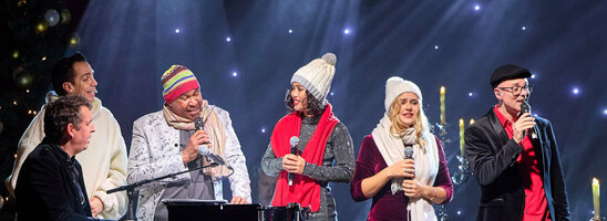 ATLANTIC Hotel Münster Firmenweihnachtsfeier im Engelsaal Eine Gruppe von Menschen singt auf einer Bühne mit festlicher Beleuchtung und Dekoration.