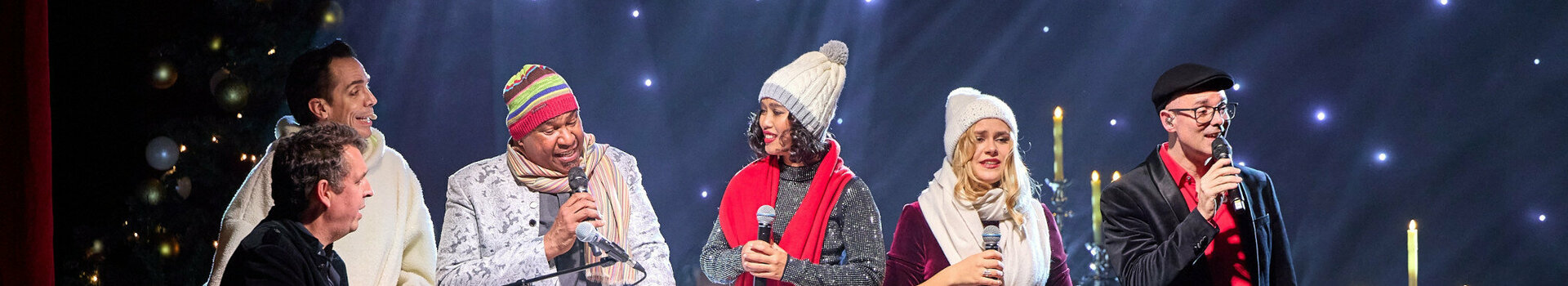 ATLANTIC Hotel Münster Firmenweihnachtsfeier im Engelsaal Eine Gruppe von Menschen singt auf einer Bühne mit festlicher Beleuchtung und Dekoration.