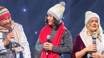 Eine Gruppe von Menschen singt auf einer Bühne mit festlicher Beleuchtung und Dekoration.
