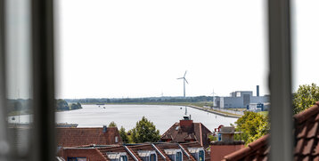 Blick aus Hotelfenster auf Fluss, Dächer, Windräder und grüne Landschaft in Bremen Vegesack.