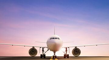 Frontansicht eines Flugzeugs auf der Landebahn bei Sonnenuntergang, symbolisiert Nähe zum Flughafen.