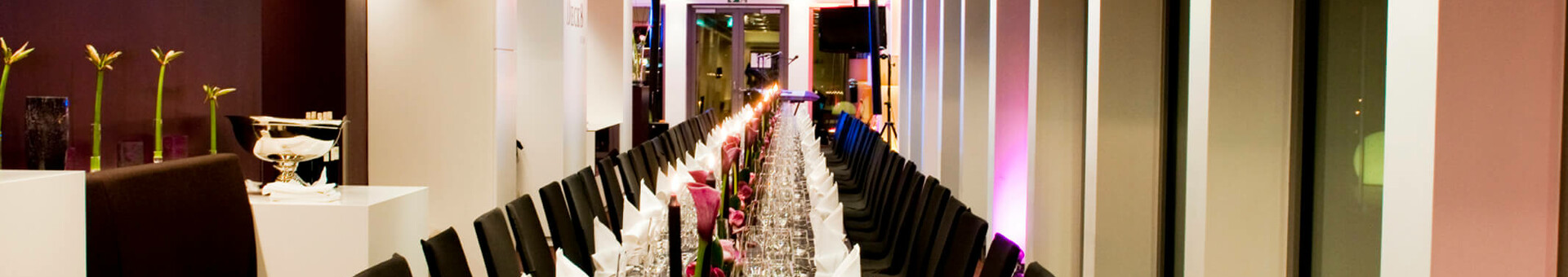 Festliche Tafel auf DECK 8 – die Bar Eleganter, festlich gedeckter langer Tisch in modernem Raum mit gedämpfter Beleuchtung im ATLANTIC Hotel Kiel.