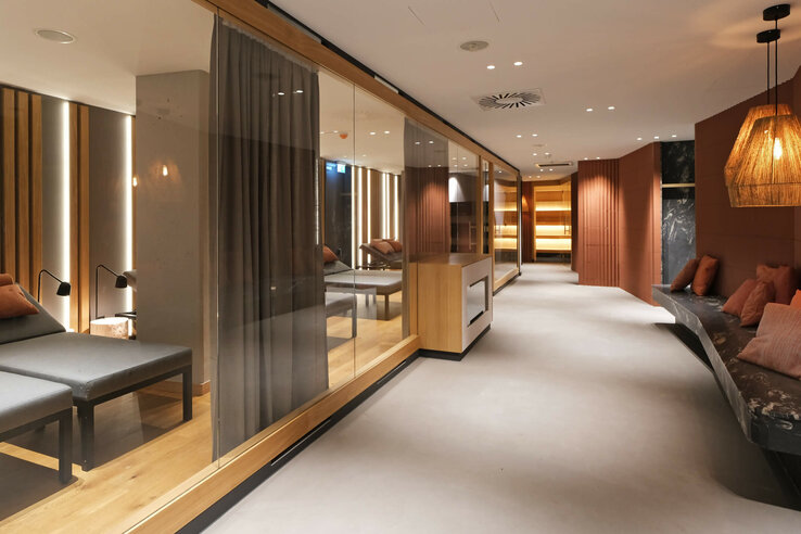 Modern relaxation area in the ATLANTIC Hotel Münster with loungers, wood and stone elements, warmly lit.