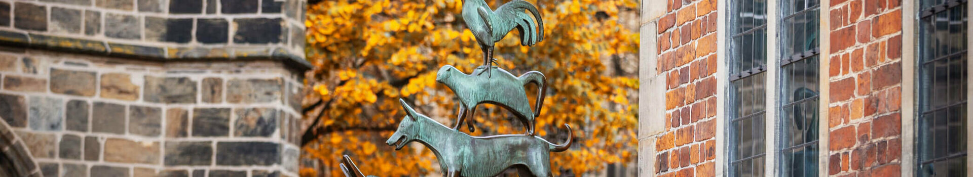 ATLANTIC Grand Hotel Bremen Goldener Autumn Stadtmusikanten Bronze statue of the Bremen Town Musicians in front of an autumnal tree and brick building.