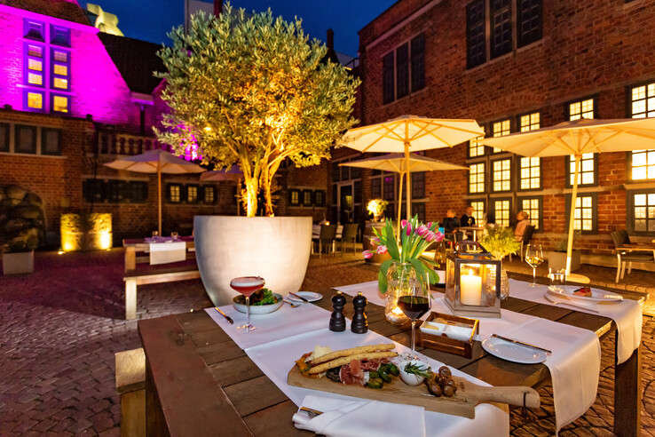 Illuminated hotel terrace with laid tables, candles, flowers and food at the ATLANTIC Grand Hotel Bremen.