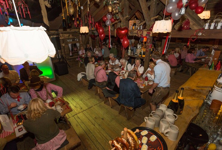 A cozy celebration in the rustic room of the ATLANTIC Grand Hotel Bremen, with guests in traditional costumes and festive decorations.