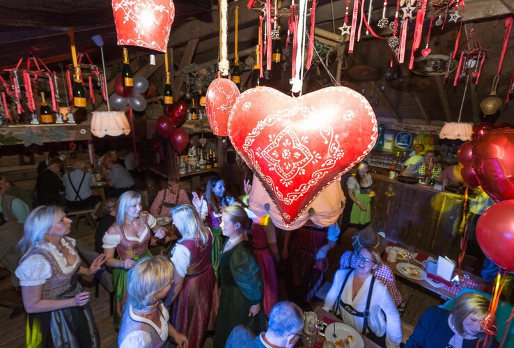 Cheerful celebration in traditional costume, red heart decorations, festive atmosphere in the ATLANTIC Grand Hotel Bremen.