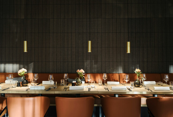 Elegantes Restaurant mit gedecktem Holztisch, Ledersesseln und Blumenvasen im ATLANTIC Hotel Münster.