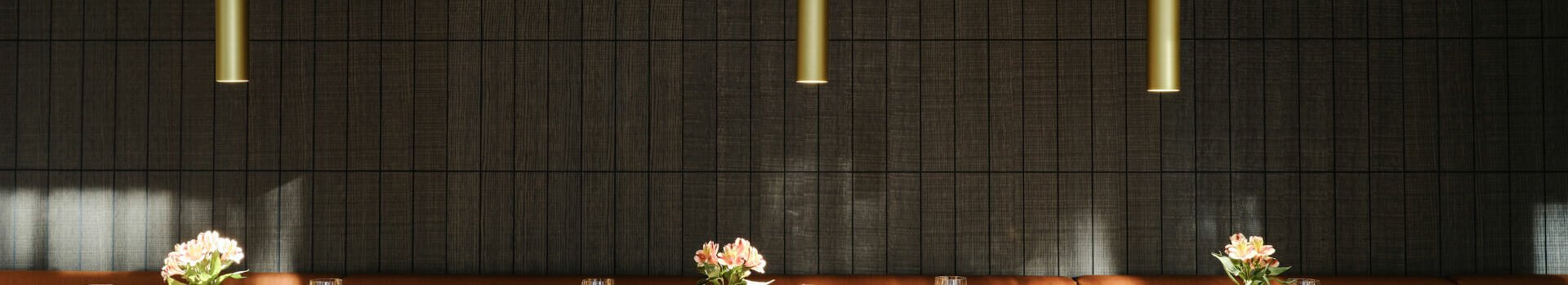 Elegant restaurant with covered wooden table, leather armchairs and flower vases at the ATLANTIC Hotel Münster.