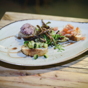 Gourmet starter with bread, spread, diced cucumber and tomatoes on a rustic wooden table in the ATLANTIC Hotel Sail City.