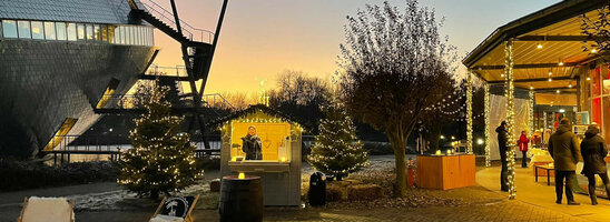 Weihnachtlich geschmückter Außenbereich des ATLANTIC Hotel Universum bei Sonnenuntergang, mit Lichterketten und Ständen.