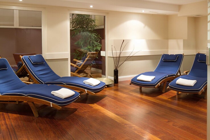 Entspannungsbereich mit blauen Liegen, Holzboden und Pflanzen im ATLANTIC Grand Hotel Travemünde.