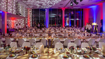 Festlich gedeckter Bankettsaal im ATLANTIC Hotel Sail City mit Kerzenlicht und bunter Beleuchtung.