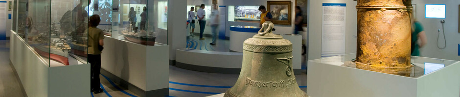 Museumsausstellung im ATLANTIC Hotel Wilhelmshaven mit historischen Artefakten, Vitrinen und Besuchern.