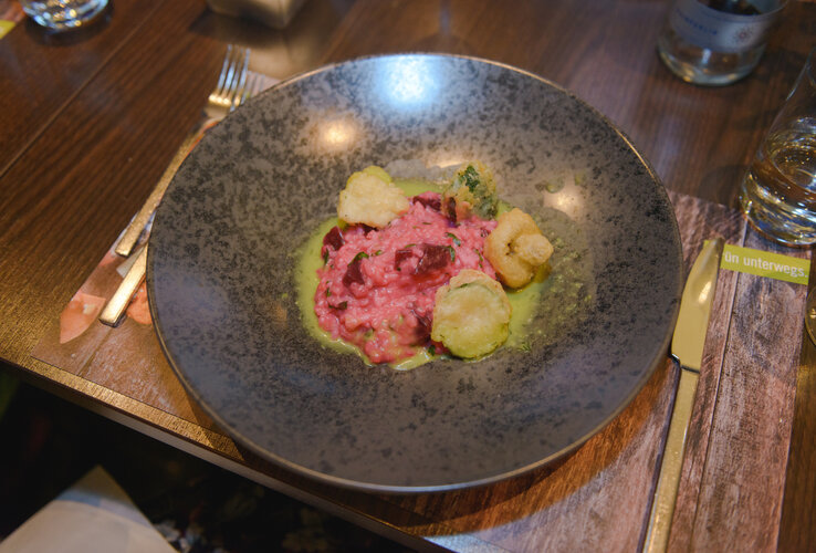 Beet risotto with fried vegetables on green puree, served on a dark plate at the ATLANTIC Hotel Sail City.