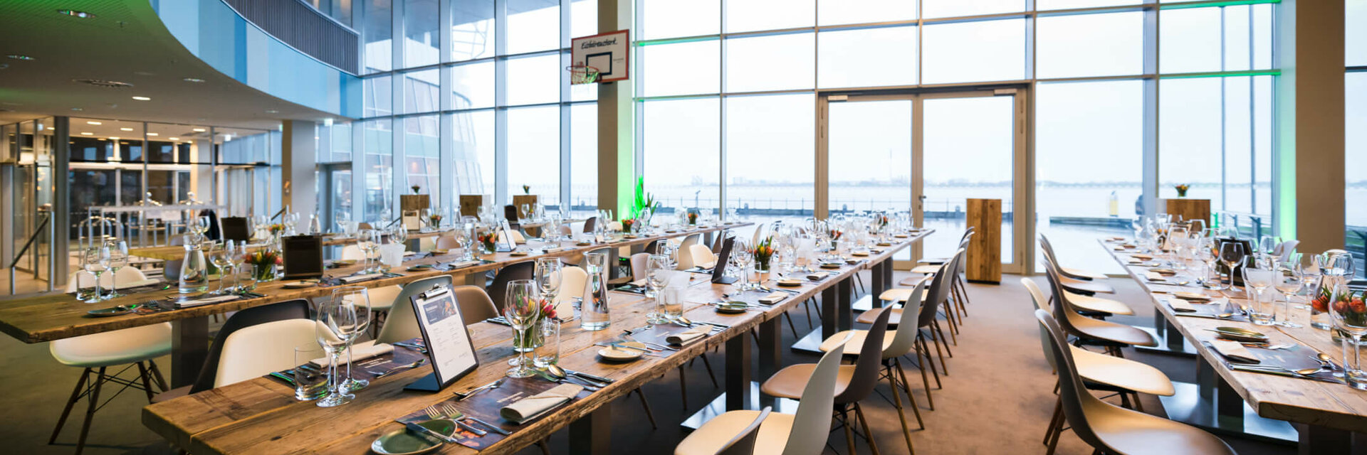 Large, modern function room in the ATLANTIC Hotel Sail City with set tables and a view of the water.