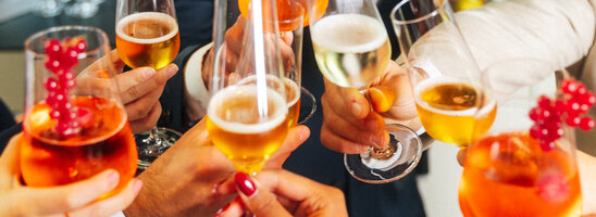 Menschen stoßen mit Sekt und Aperolgläsern an.