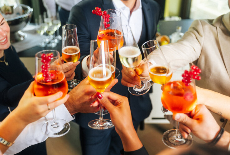 Menschen stoßen mit Sekt und Aperolgläsern an.