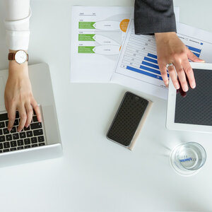 Event technology for your conference in the ATLANTIC Hotel Galopprennbahn Two people work at a table with a laptop, tablet, notepads and drinks at the ATLANTIC Hotel Galopprennbahn.