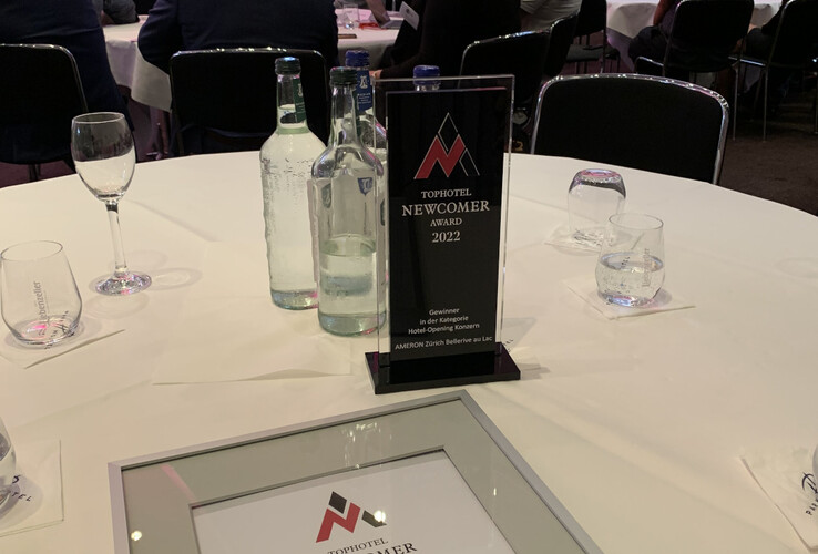 Event with Tophotel Newcomer Award 2022 for ATLANTIC Hotel Münster, certificate and trophy on table.