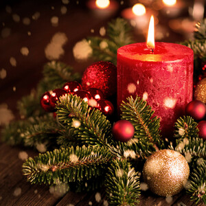 Merry Christmas | ATLANTIC Grand Hotel Travemünde Rote Kerze mit Tannenzweigen und roten, goldenen Kugeln, festlich dekoriert.