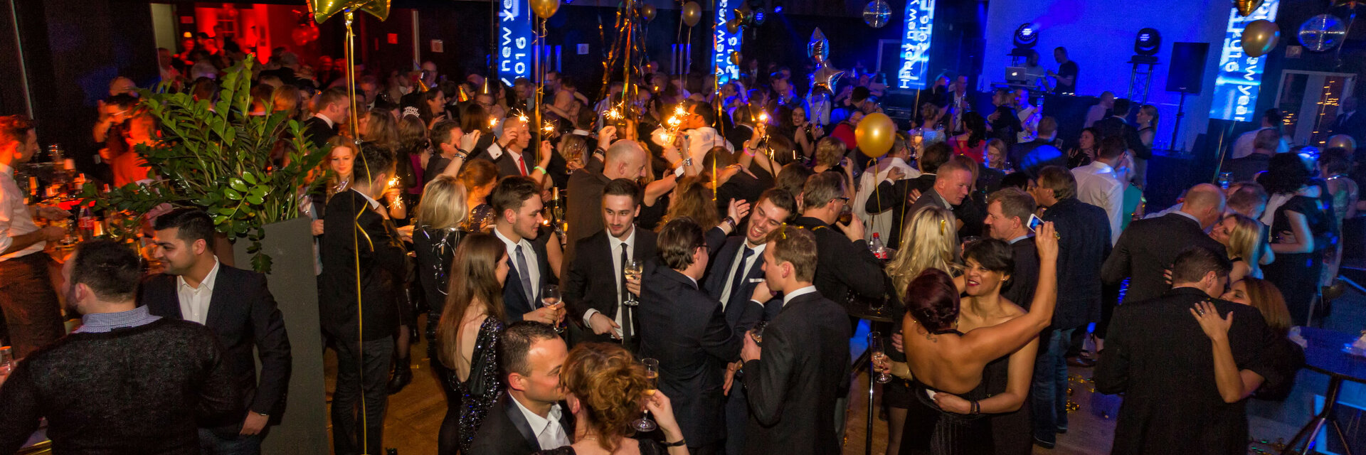 Festive celebration at the ATLANTIC Grand Hotel Bremen: Elegant guests dance and celebrate under golden balloons and lights.