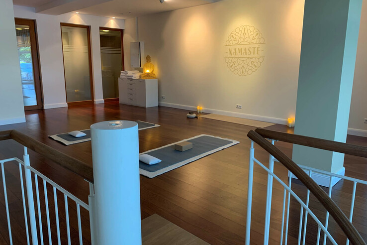 Heller Yoga-Raum im ATLANTIC Grand Hotel Travemünde mit Matten, Kissen und Buddha-Statue, entspannte Atmosphäre.