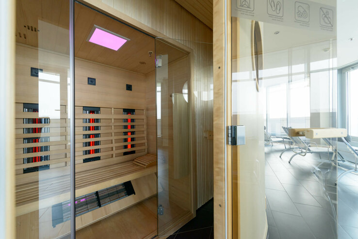 Modern sauna with glass front in the ATLANTIC Hotel Sail City, view of loungers and large windows in the background.