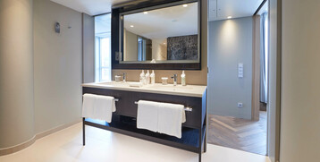 Modern hotel bathroom with large mirror, double washbasin, towels and care products at the ATLANTIC Grand Hotel Bremen.
