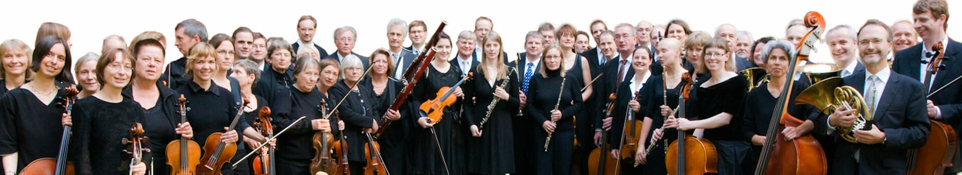 Eine Gruppe von Musikern in schwarzer Kleidung mit verschiedenen klassischen Instrumenten wie Celli und Geigen.