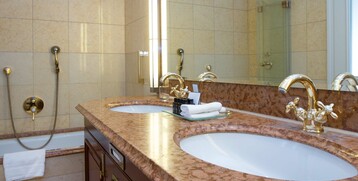 Luxurious bathroom in the ATLANTIC Grand Hotel Travemünde with double washbasin, golden fittings and marble surfaces.
