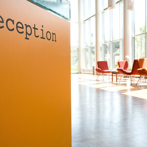 Heller Lobbybereich des ATLANTIC Hotels mit oranger Rezeption und roten Sesseln vor großen Fenstern.