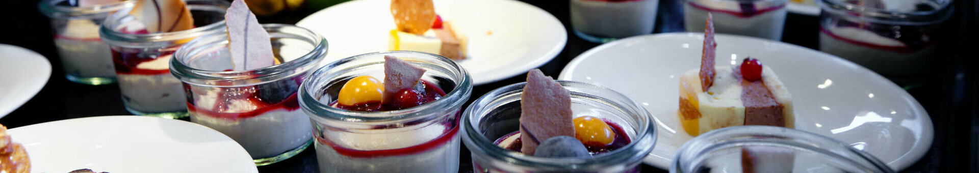 Dessertbuffet mit frischen Früchten und kleinen Gläsern mit Panna Cotta, dekoriert mit Beeren und Gebäck im ATLANTIC Hotel.